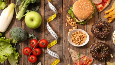 Healthy foods like vegetables and apples on left, junk foods like burgers and donuts on right, divided by a measuring tape.