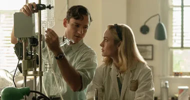 A man and woman in lab coats work together on scientific equipment in a well-lit laboratory.
