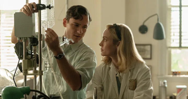 A man and woman in lab coats work together on scientific equipment in a well-lit laboratory.