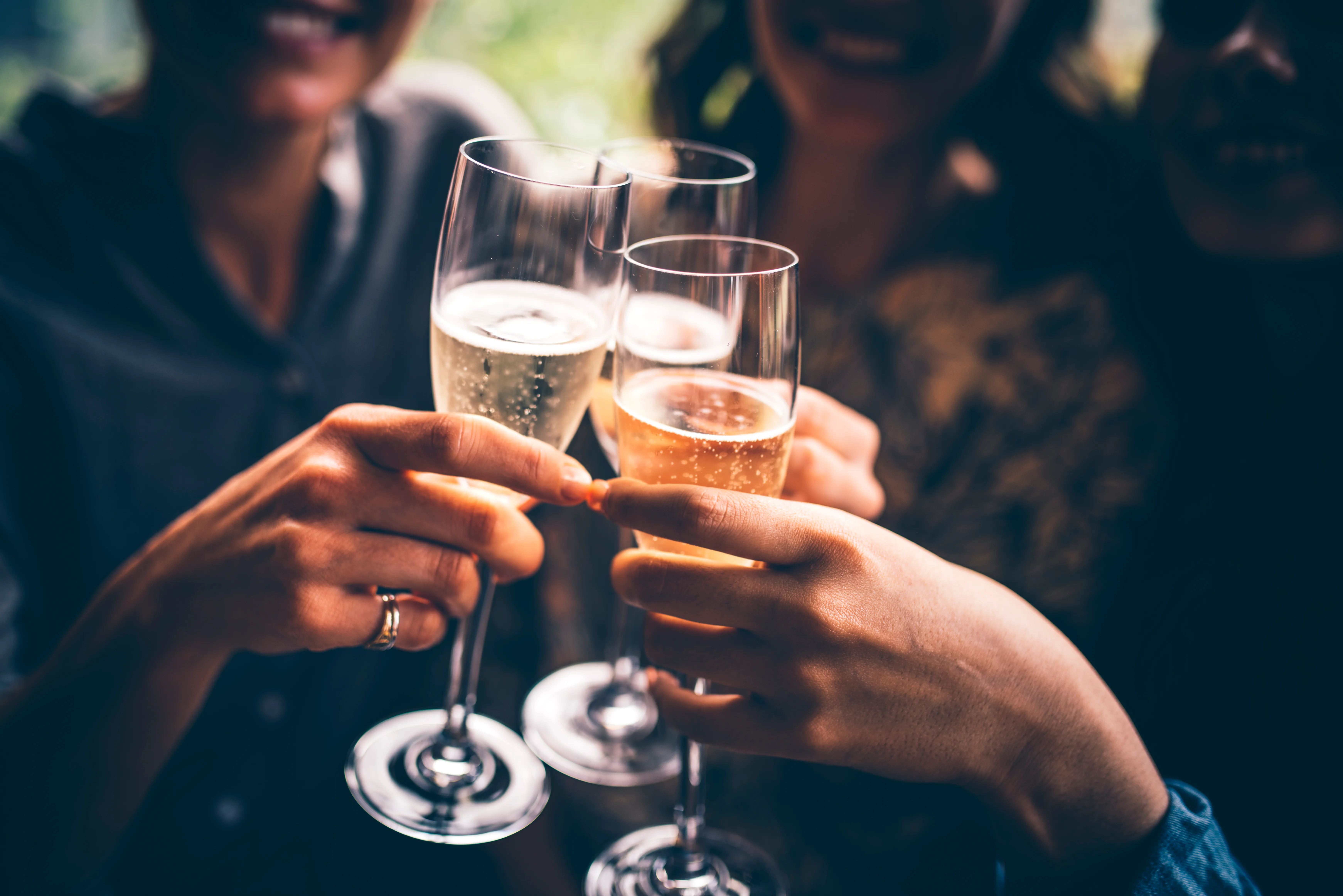 Three female friends celebrating with champagne. They are sitting in a bar and toasting with glasses of champagne.