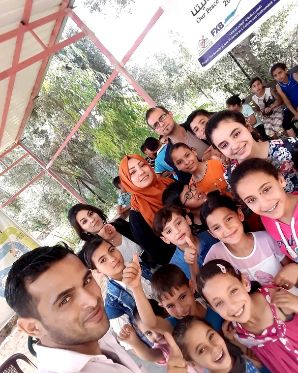 Rami is outdoors with a group of smiling children and their teachers in Palestine.
