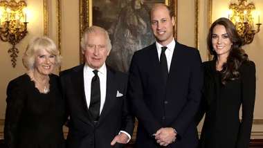 Four people posing in formal attire in an elegant room with ornate decor.