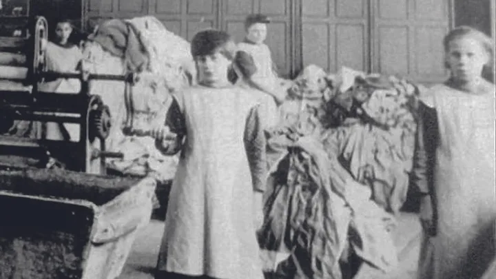 Children working in a textile factory, handling fabrics and machinery, dressed in aprons, early 20th century.