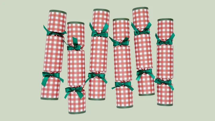 Red and white checkered Christmas crackers with green ribbon on a light green background.