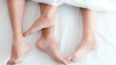 Couple under covers in bed to represent having sex