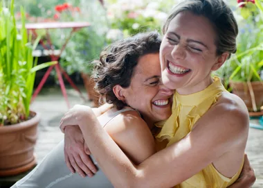 two women hugging on a balcony