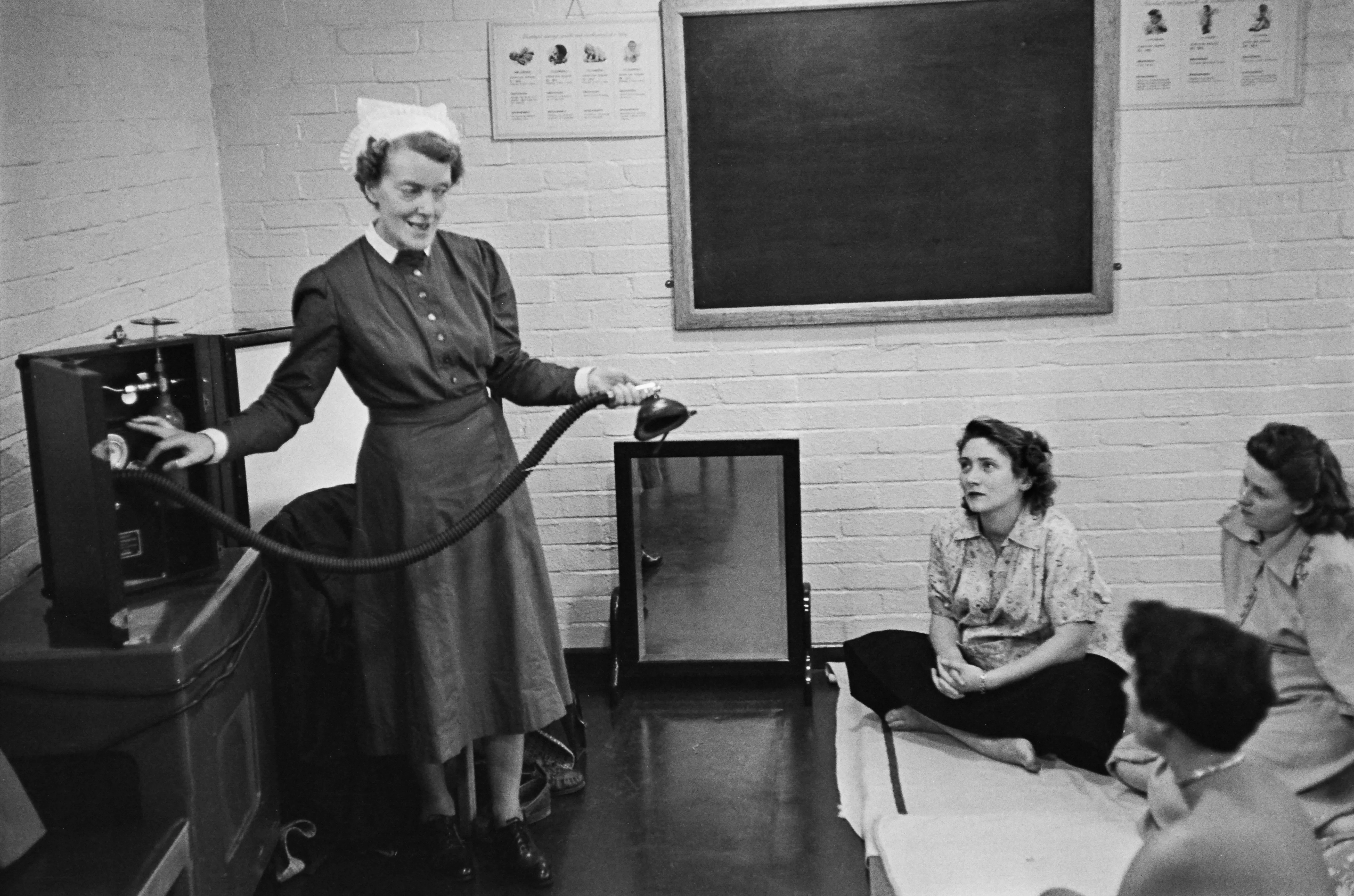 A midwife shows a pain relief breathing apparatus for nitrous oxide to pregnant women at an antenatal class at a hospital, UK, 1956. Original Publication: Picture Post - 9111 - Analgesia (In Childbirth) - unpub. (Photo by Grace Robertson/Picture Post/Hulton Archive/Getty Images).