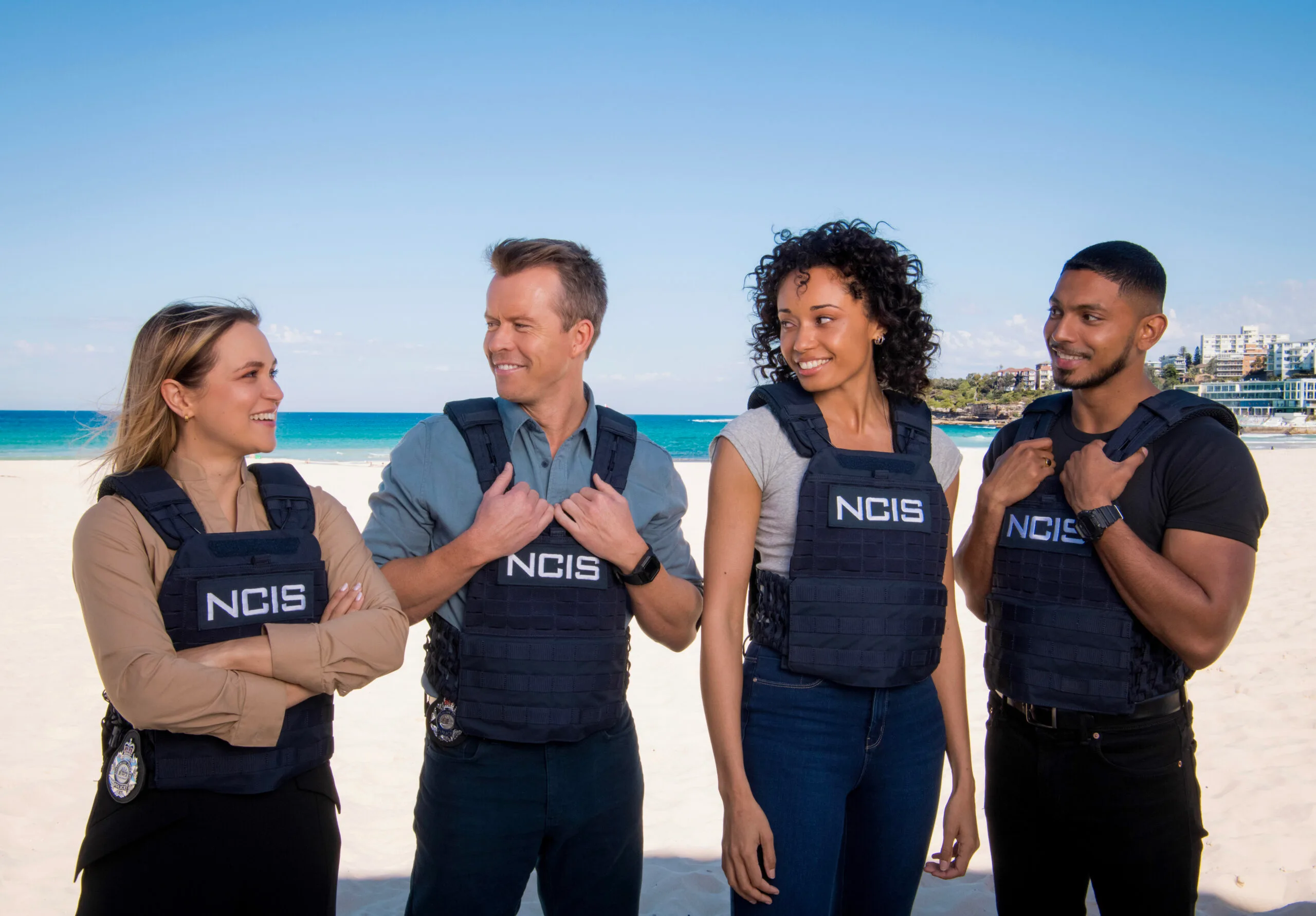 L-R: Tuuli Narkle as AFP Liaison Officer Constable Evie Cooper, Todd Lasance as AFP Liaison Officer Sergeant Jim  'JD' Dempsey, Olivia Swann as NCIS Special Agent Captain Michelle Mackey and Sean Sagar as Special Agent DeShawn Jackson at Bondi Beach, on the set of NCIS: Sydney.  PHOTO CREDIT: Daniel Asher Smith/Paramount+    © TM & © 2023 CBS Studios Inc. NCIS: Sydney and related marks and logos are trademarks of CBS Studios Inc. All Rights Reserved.