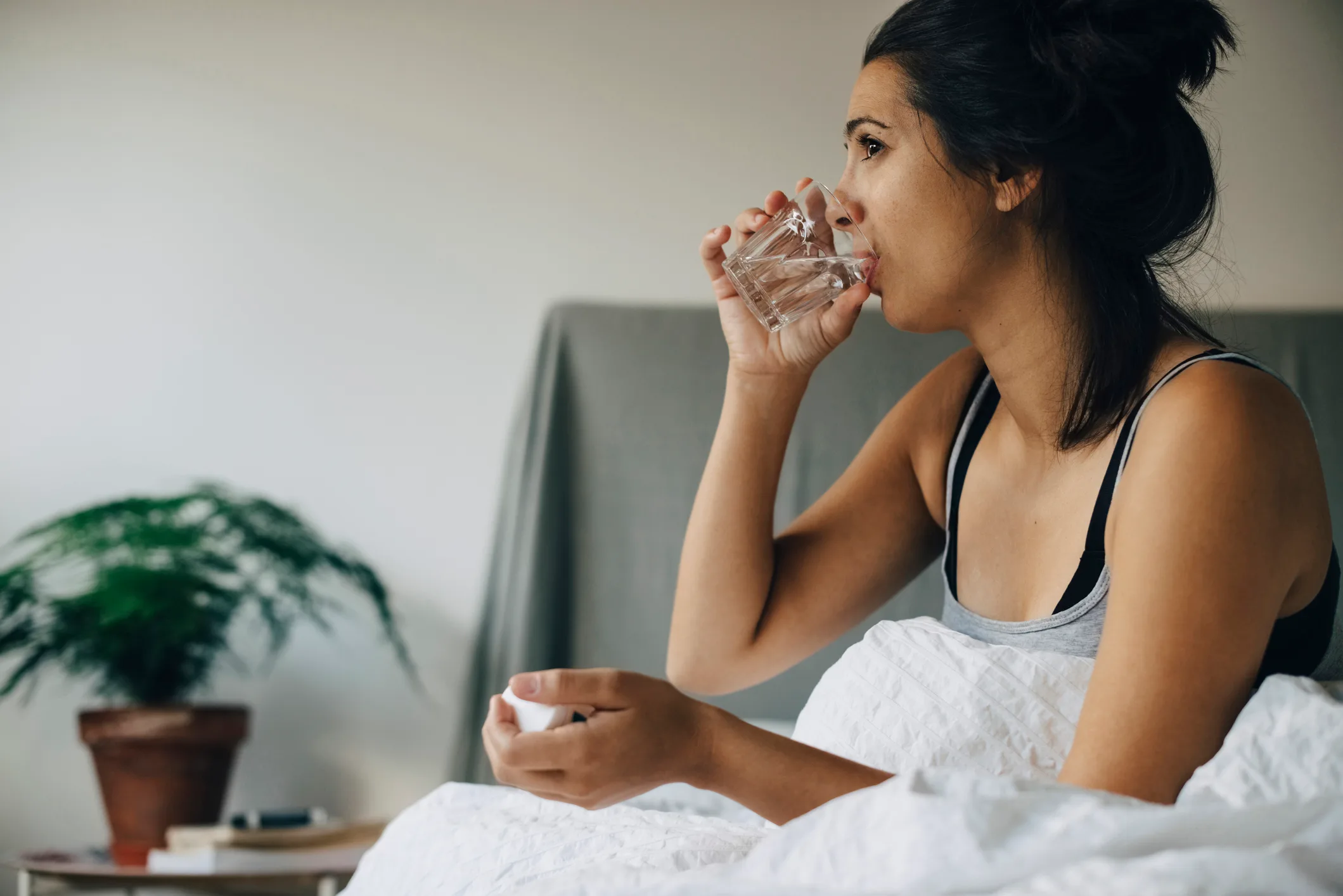 woman drinking water in bed taking medication