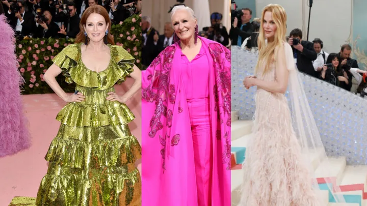 Three women in elegant gowns pose on a red carpet with photographers in the background.