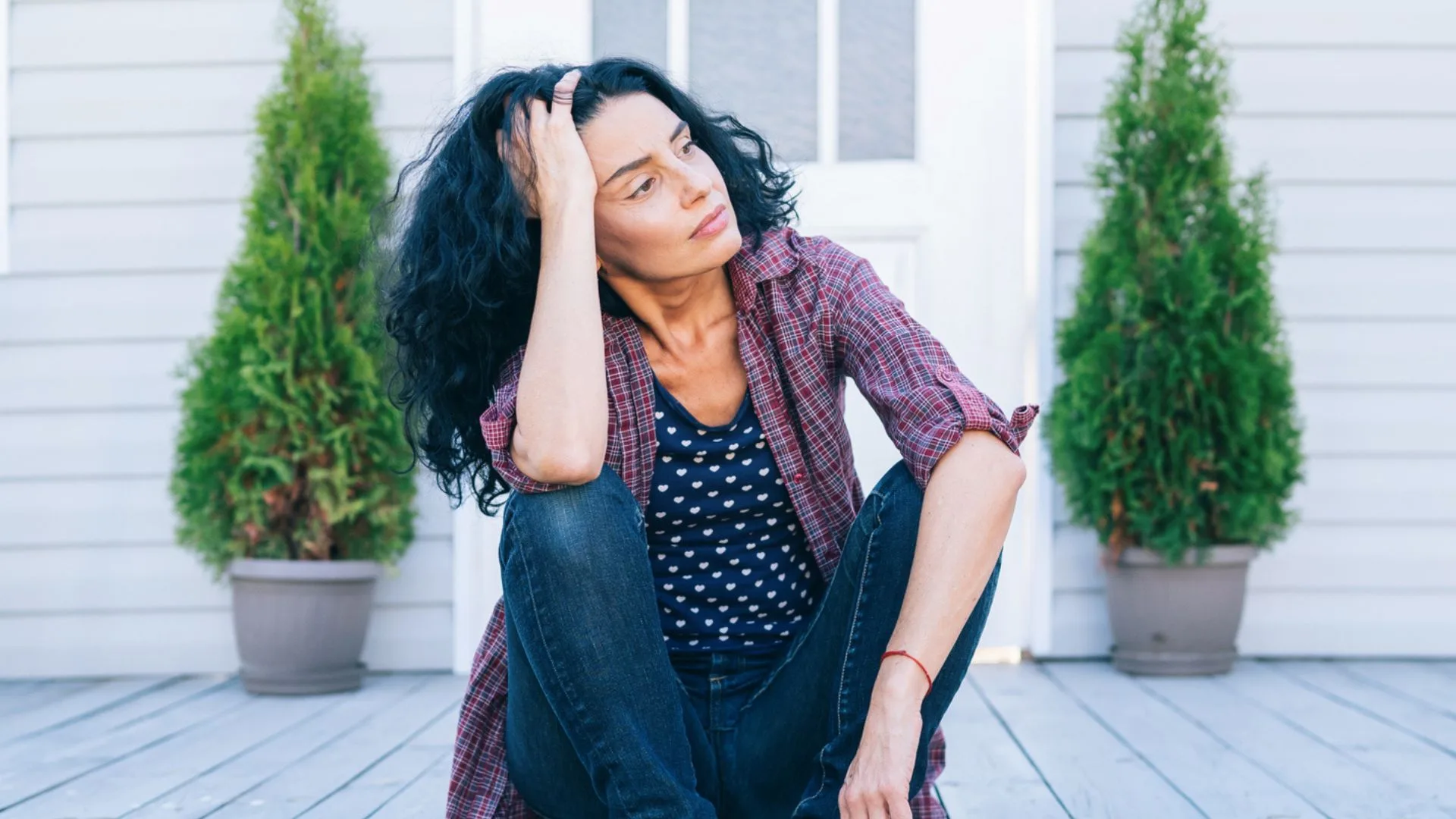 Woman sitting on front verandah with a tired expression