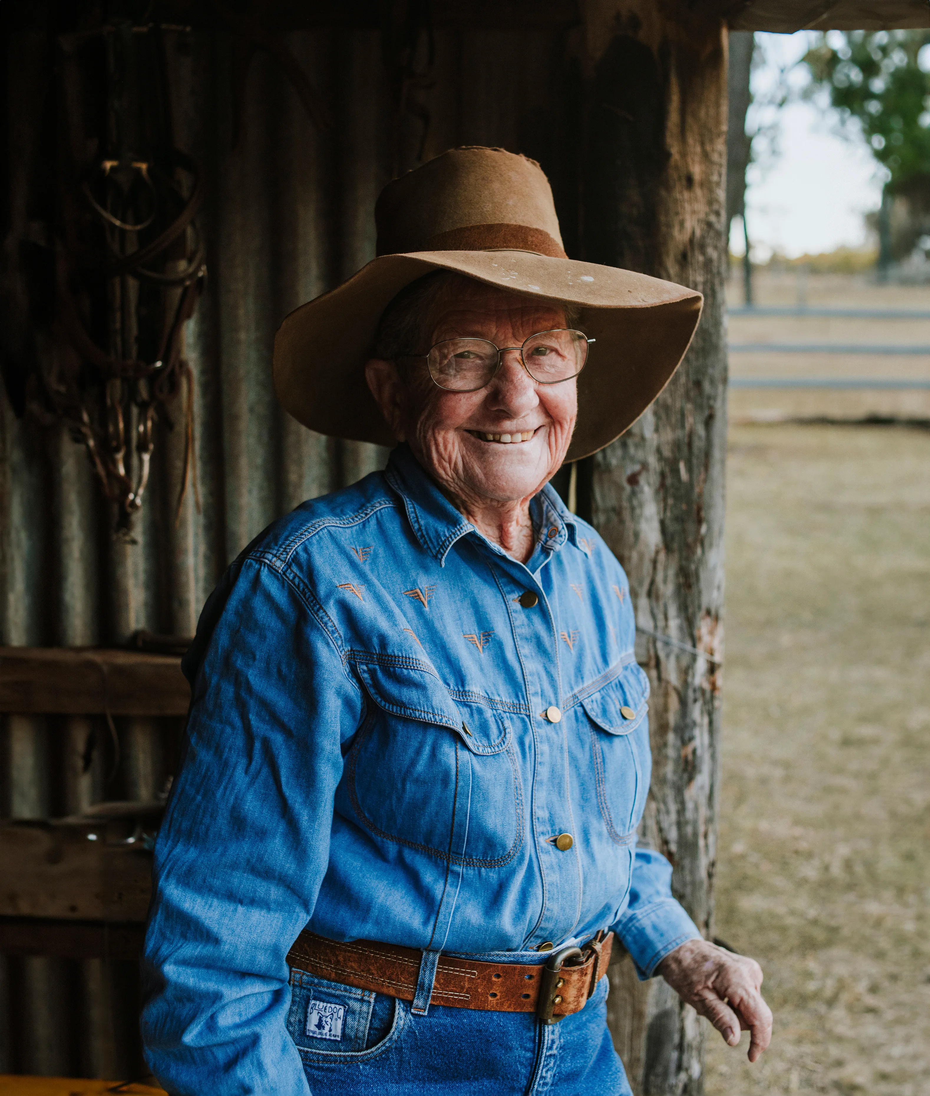 Girlie smiles at the camera, wearing her old Akubra hat and a blue denim shirt.