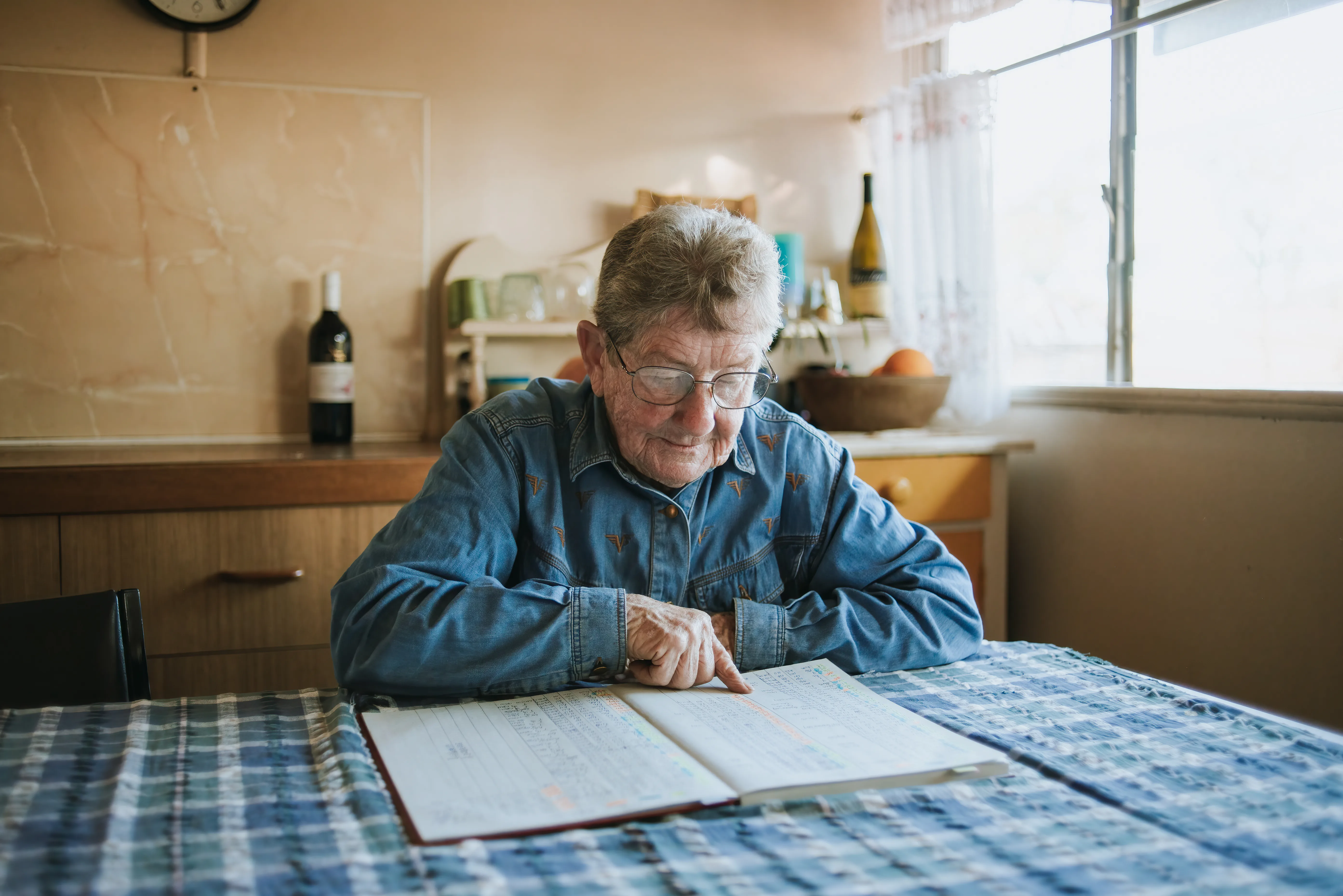 Girlie sits at her dining table and looks through a notebook.