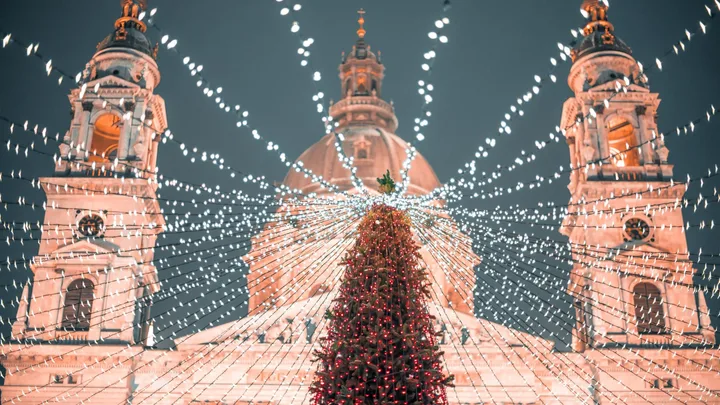 Christmas tree with lights in front of a lit-up domed building, creating a festive atmosphere at night.