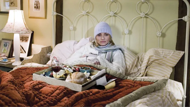 Woman in bed wearing a knit hat with breakfast tray, cozy setting.