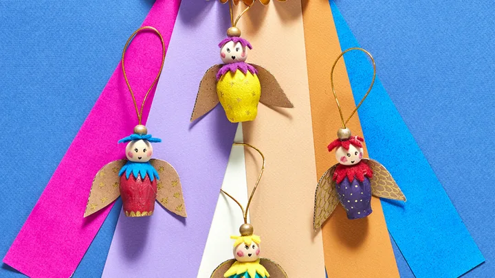 Colorful handmade paper roll cherub ornaments with felt wings on a vibrant geometric background.