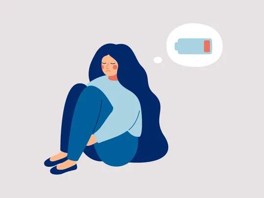 An illustration of a woman hugging her knees with a flat battery in her thoughts. Symbolic of symptoms of burnout.