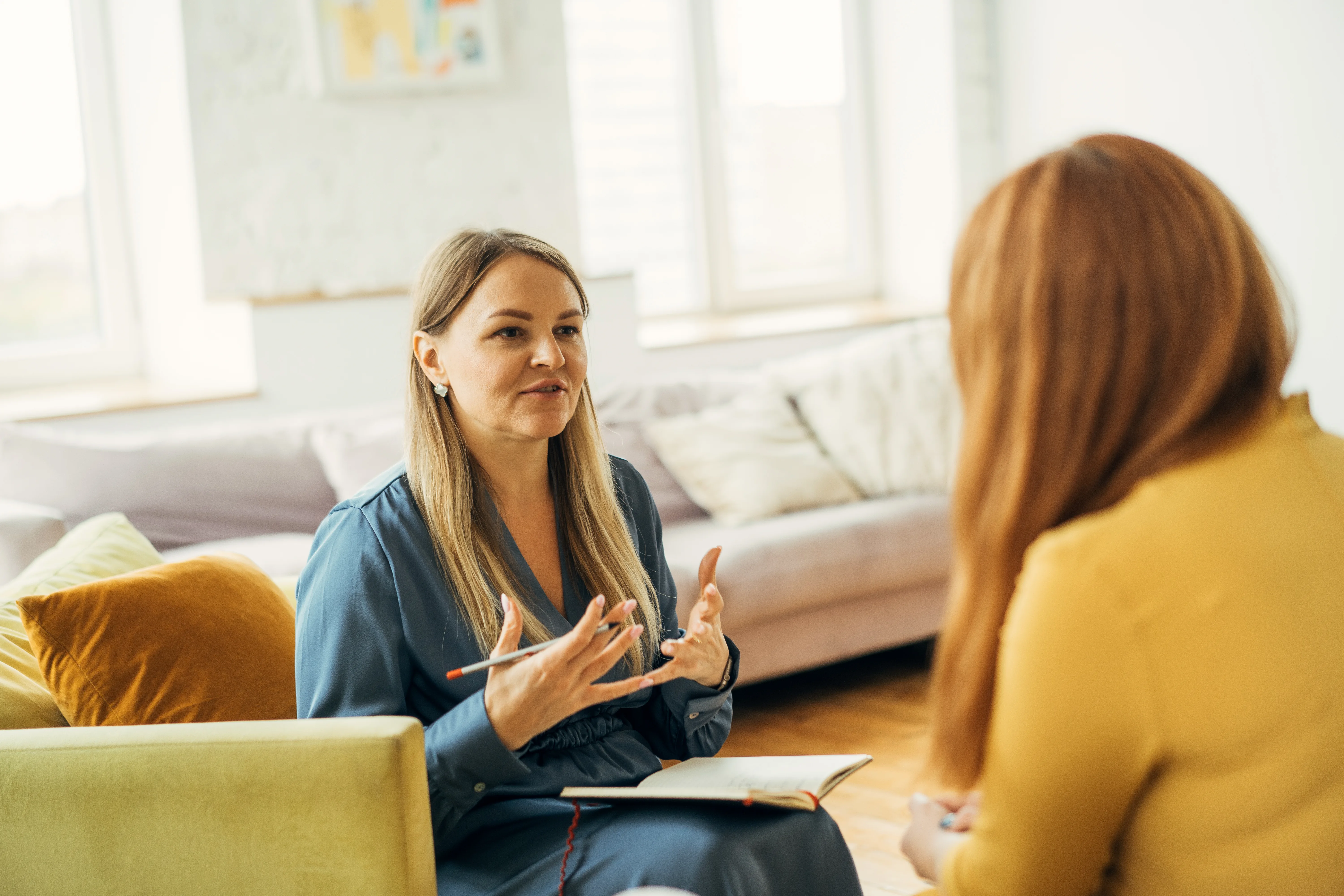 Two women sitting in therapy to discuss symptoms of burnout.