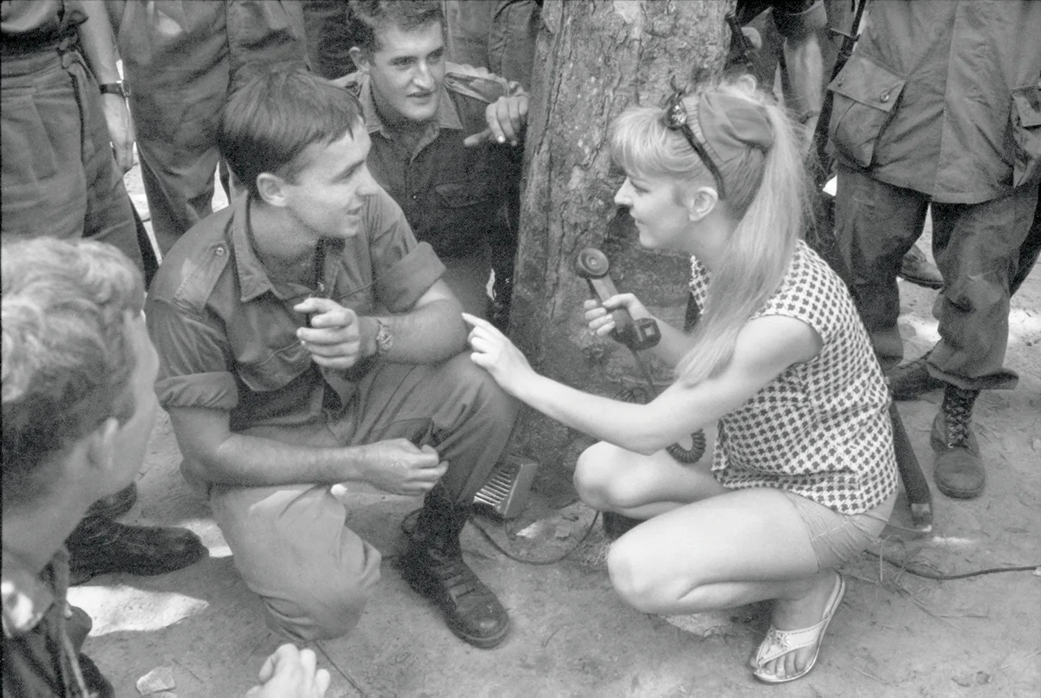 A black and white photo of a female performer talking to a male soldier. 