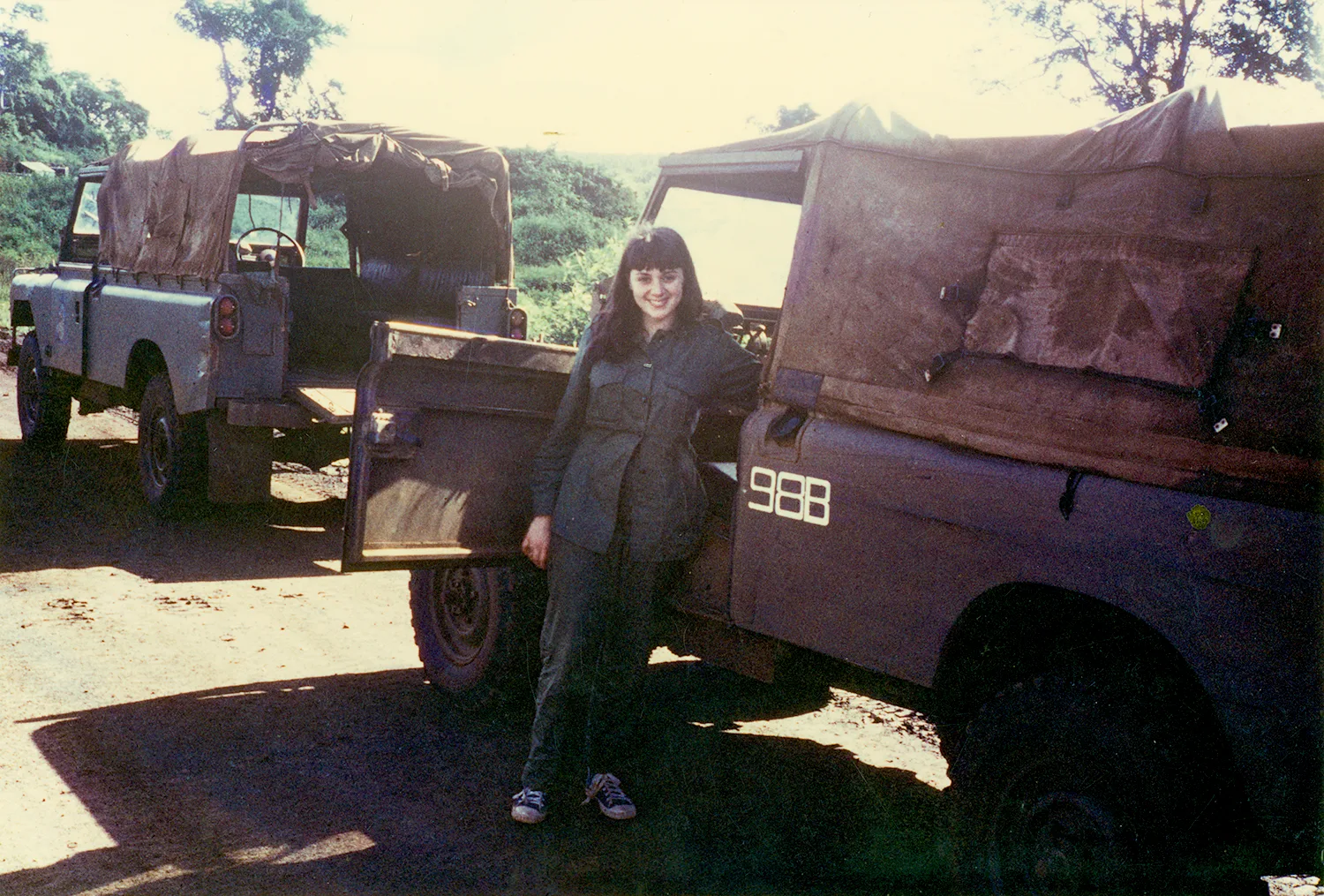 A woman standing in front of a war vehicle. 