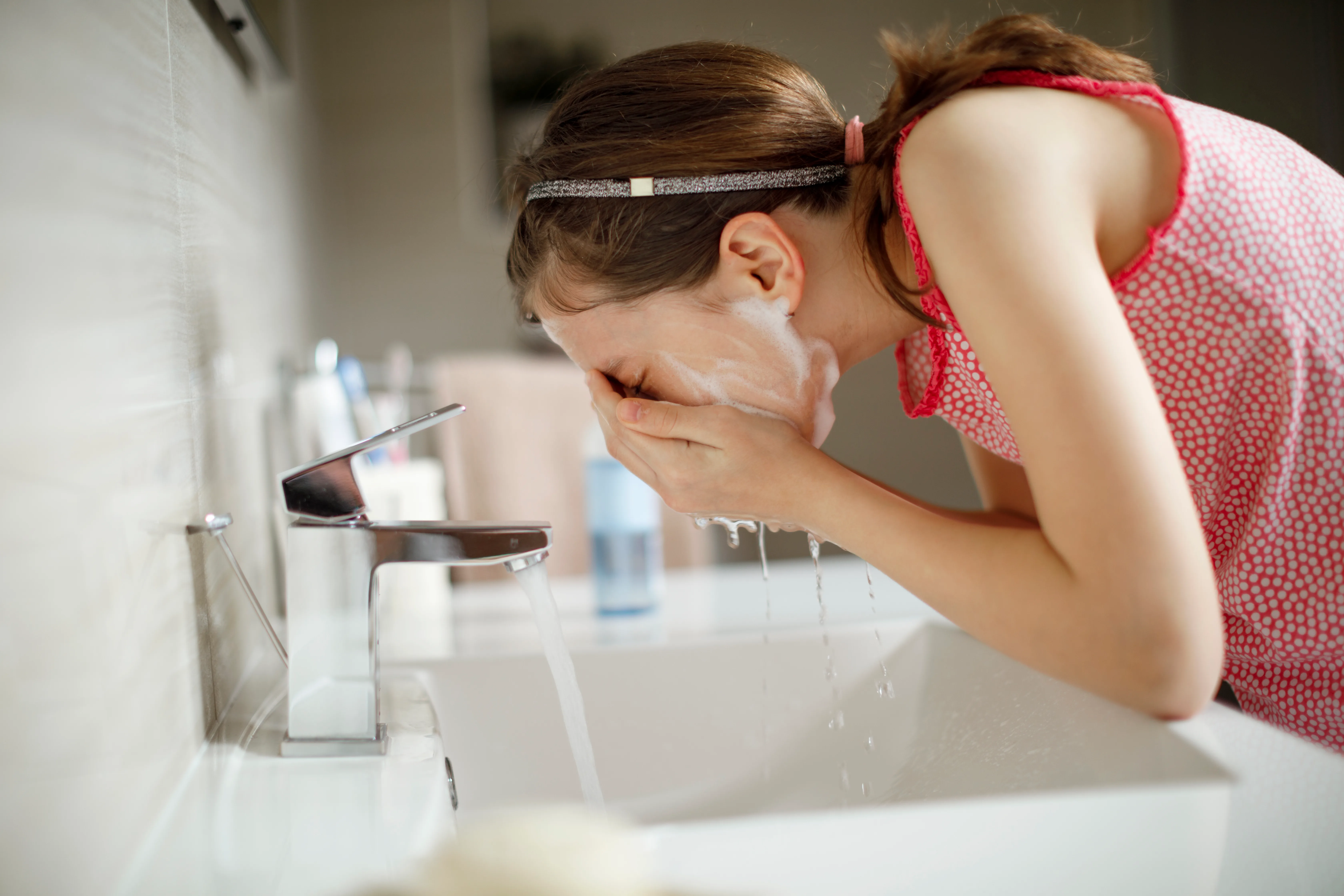 teenage girl washing her face with water