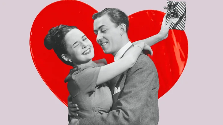 A couple embracing with a red heart background; the woman is winking and holding a small gift.
