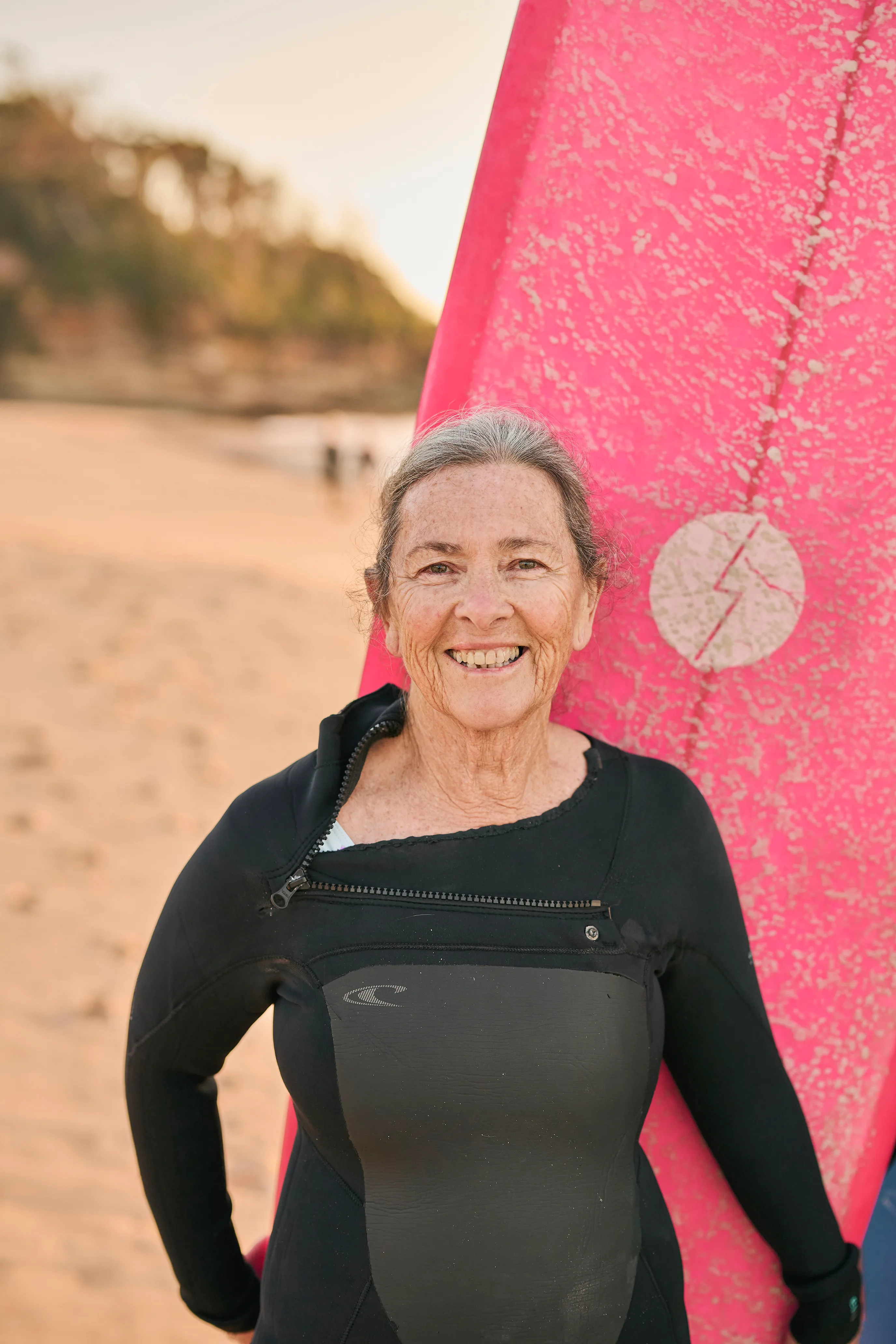 Australian female surfer Donna Miles in her wetsuit with her surfboard.