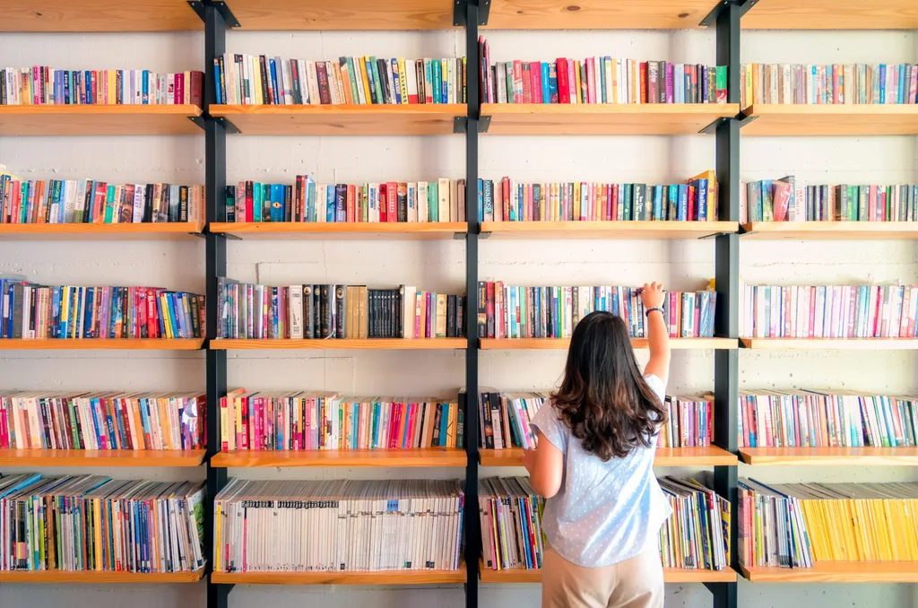 Asian woman selecting a book from a shelf