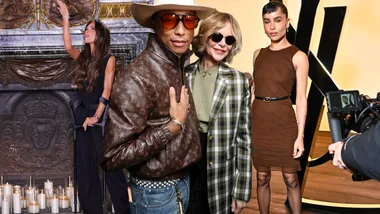 Celebrities at a fashion event, one woman with crutches, another in brown dress, and a man in a patterned jacket and hat.