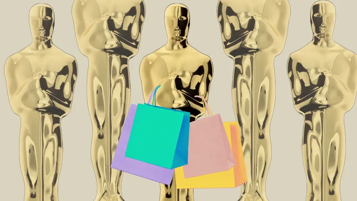 Golden Oscar statues with colorful shopping bags hanging from one.