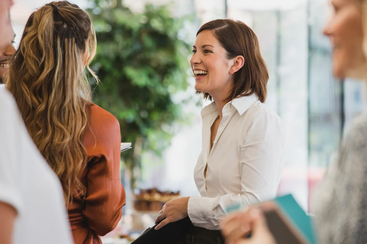 Two women in a work setting having a light-hearted conversation.