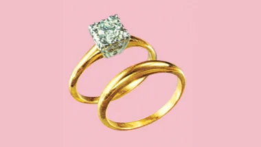 Two gold rings, one with a diamond, on a pink background.