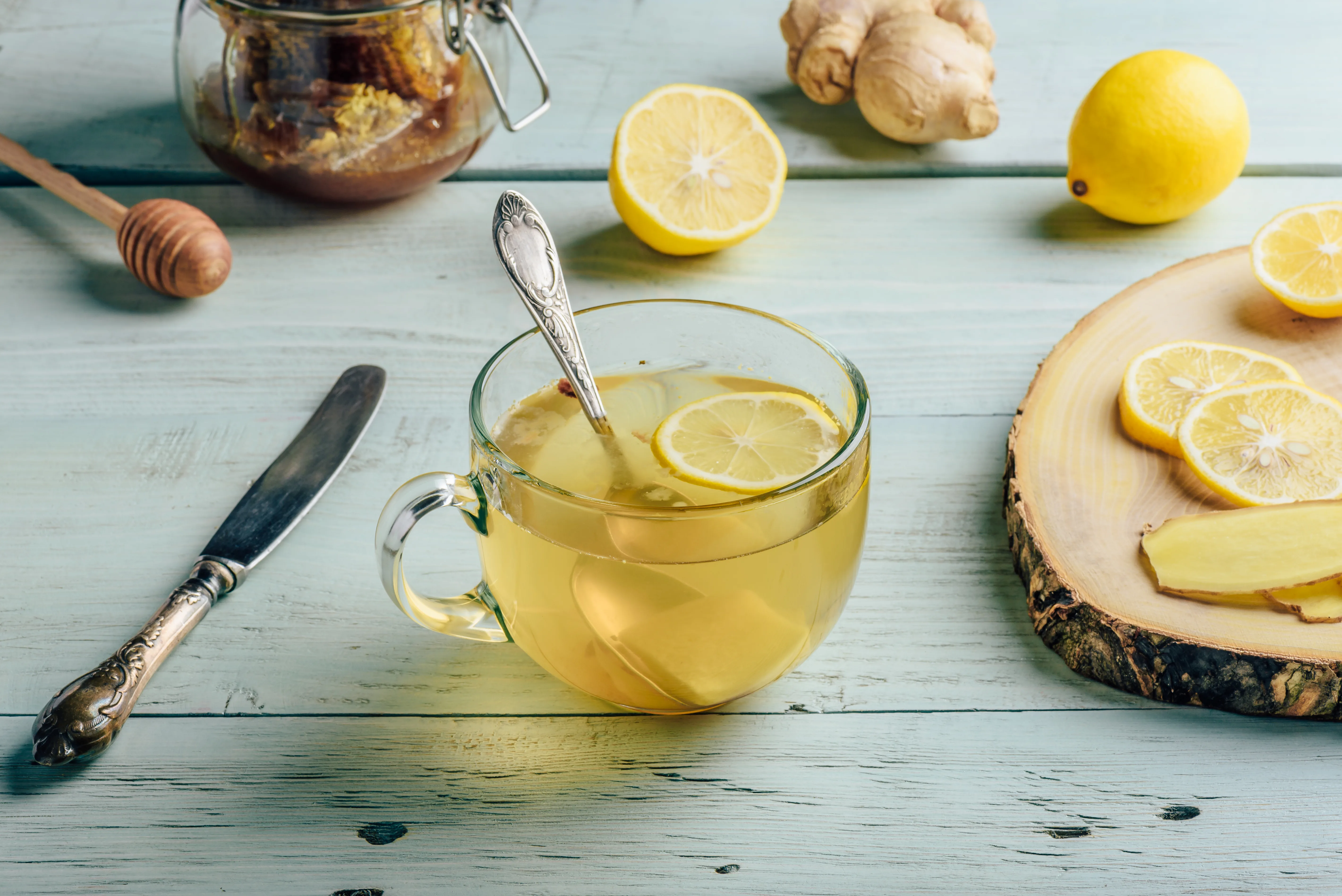 Cup of tea with lemon, honey and ginger over wooden surface