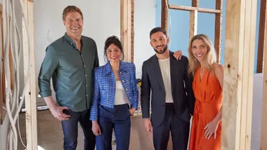 Four people standing together in a partially constructed room, smiling at the camera.