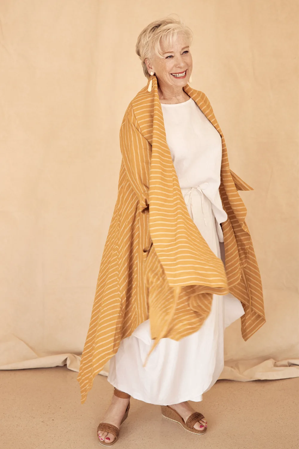 Maggie Beer in a white outfit and yellow cardigan. 