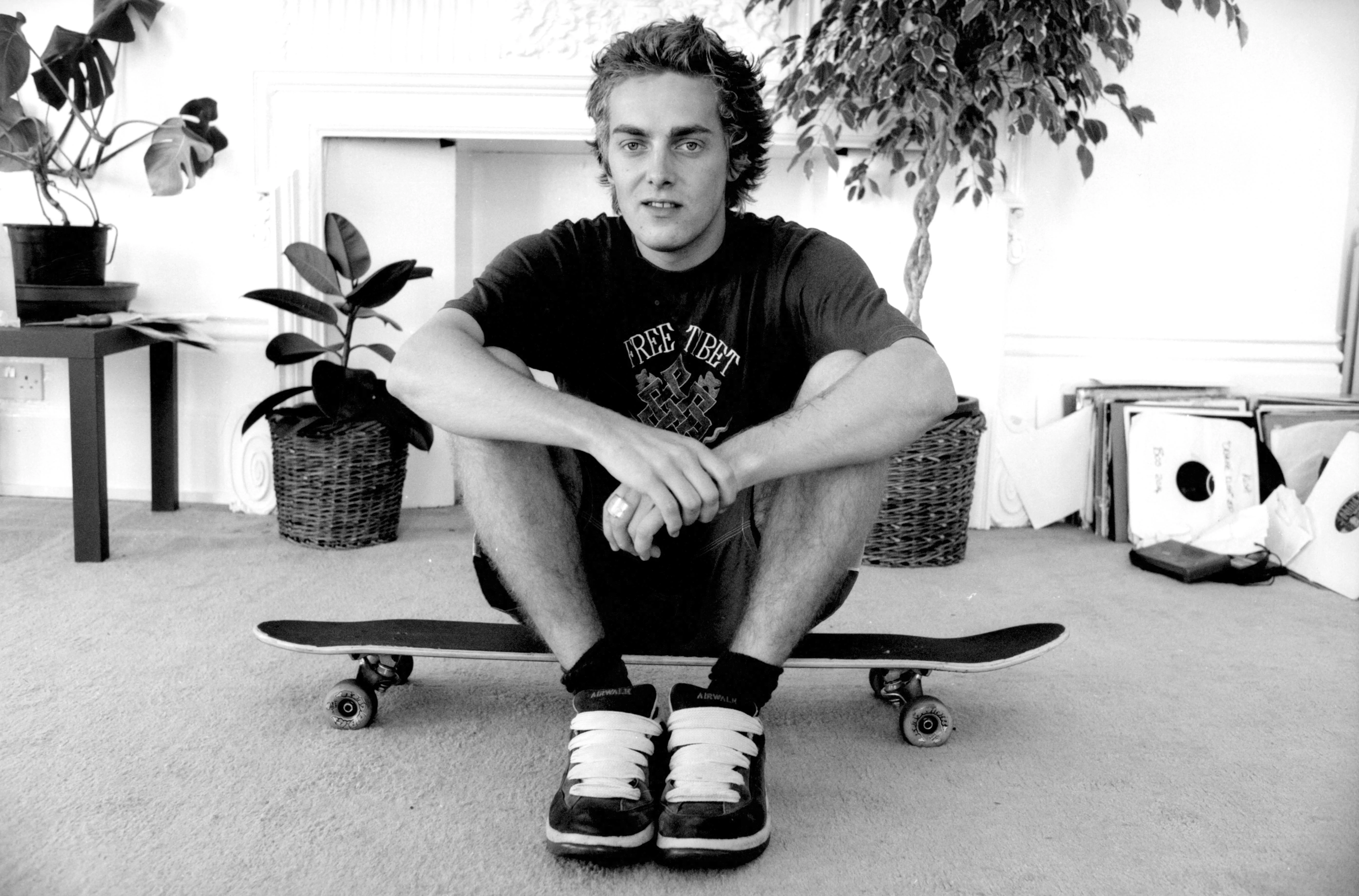 DJ Adam Freeland sitting on a skateboard wearing a Free Tibet slogan t shirt, 1990's