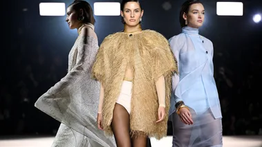 Models showcasing diverse outfits at a fashion show runway, including a gold textured ensemble.