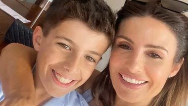 A woman and a young boy smiling for a selfie indoors.