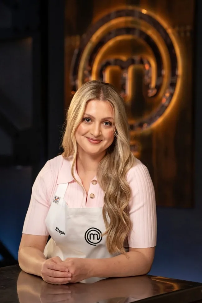Woman in a MasterChef apron smiles in front of a MasterChef logo.