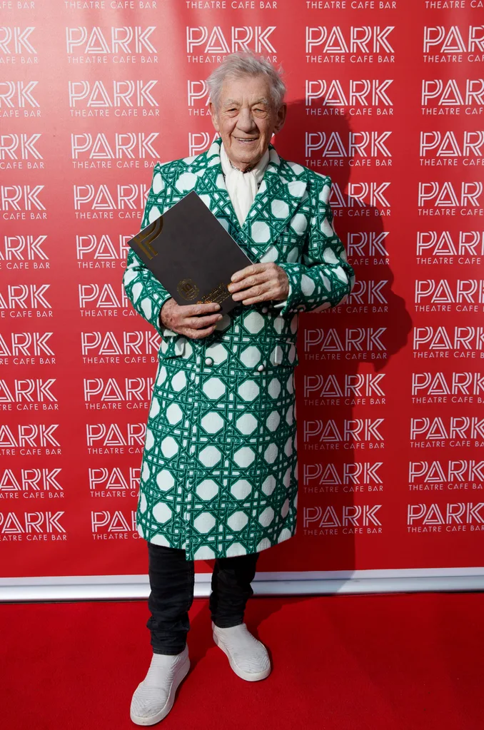 Man in a patterned coat holds a folder on a red carpet in front of Park Theatre Cafe Bar backdrop.