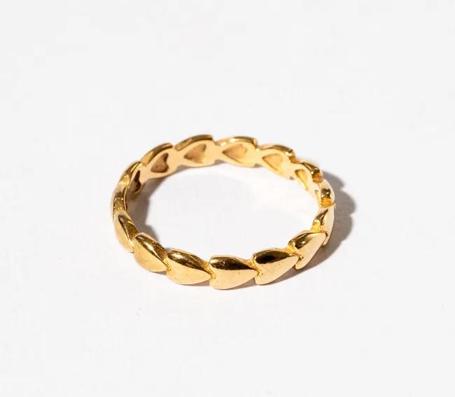 Gold heart-patterned ring on a white background.