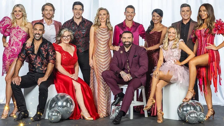Group photo of twelve people dressed in colorful costumes with disco balls on the floor.