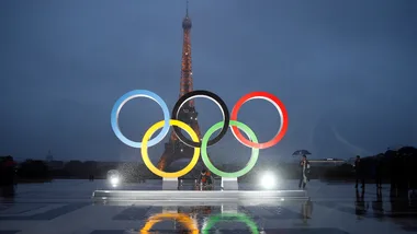 Olympic rings in front of the Eiffel Tower in Paris at night.