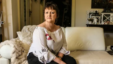 Middle-aged woman sitting on a white sofa in a cozy living room.