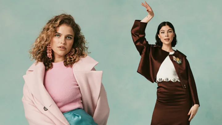 Two women posing stylishly against a green backdrop; one in pink and blue, the other in brown and white attire.