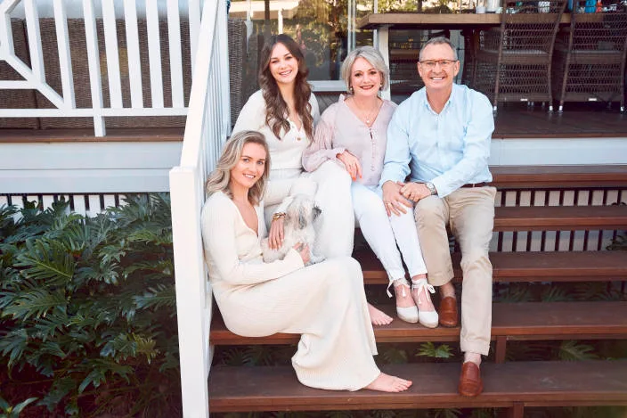 Ariarne sits on the wooden steps of her family home with sister Mia, mum Robyn, dad Steve, and Lucy, the family dog.