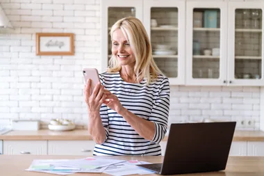 Smiling middle aged woman using smartphone for payment utility bill from online banking. Female entrepreneur communicate with customers, sending message by cell phone and enjoy working