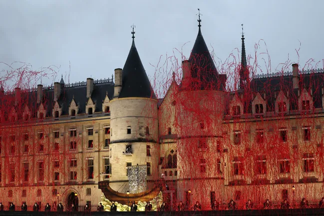 Historic building with illuminated red streamers and people standing in front. Evening setting.