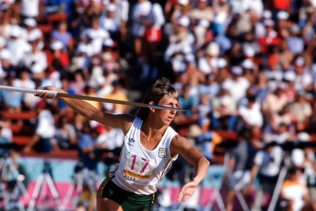 Athlete in action throwing a javelin at a crowded stadium during the Olympics.
