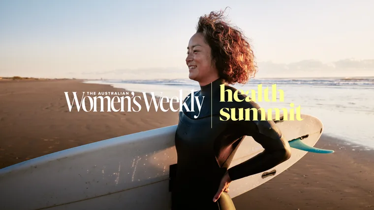 Woman with surfboard on beach at sunset, text overlay "The Australian Women's Weekly | health summit".